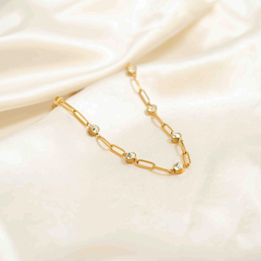 Détail du collier Éclat doré et de ses cristaux sur tissu clair